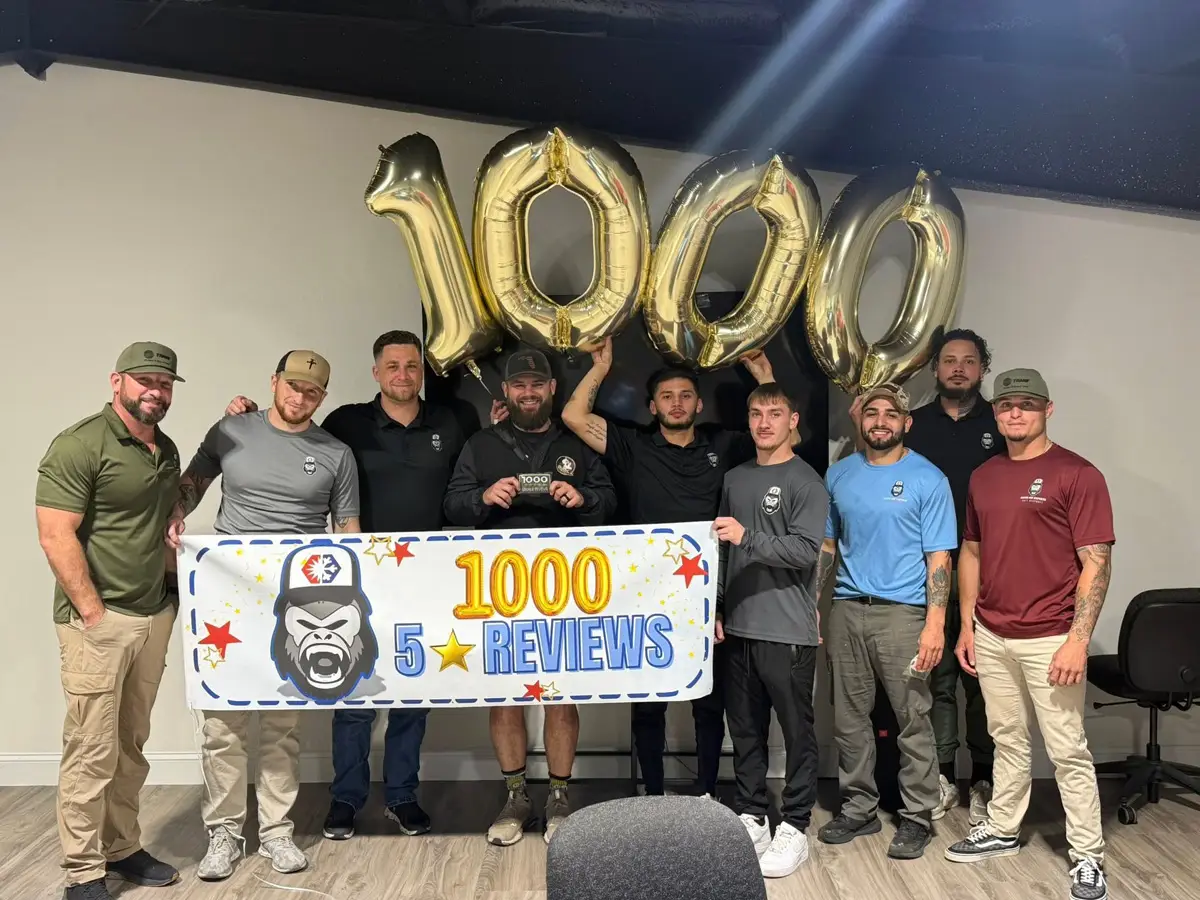 Team of men posing with gold 1000 balloons and a banner celebrating 1,000 five-star reviews